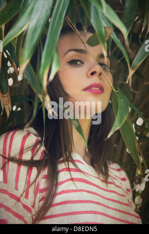 Woman Peering Through Greenery Stock Photo