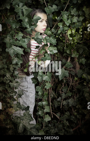 Woman Peering Through Lush vines Stock Photo