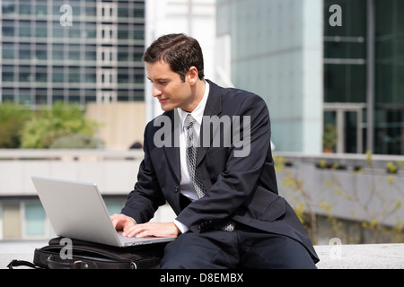 Businessman sat using laptop in the city Stock Photo