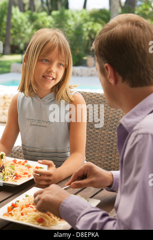 Father and daughter eating pasta together alfresco Stock Photo