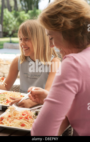 Mother and daughter eating pasta together alfresco Stock Photo