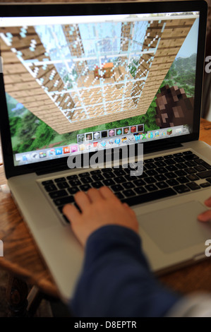 An 8 year old boy playing minecraft on his computer  Apple IPAD in his bedroom at home. Stock Photo