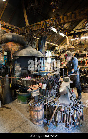 A Blacksmith heating metal in the hot coals of the fire. Stock Photo