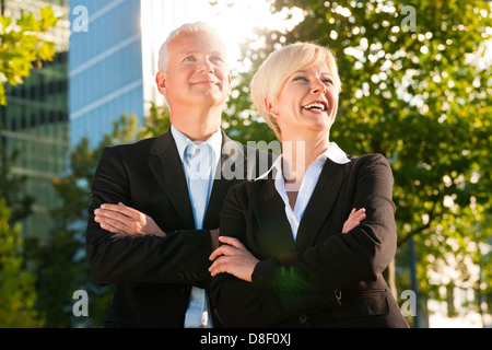 Business people - mature or senior - standing in a park outdoors in front of a office building Stock Photo