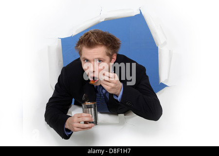 Businessman eating beans from a tin Stock Photo