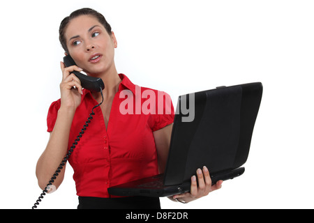 Secretary holding a laptop while talking on the phone Stock Photo