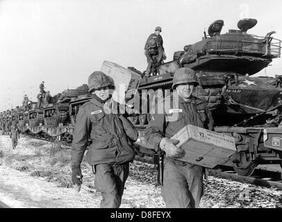 American soldiers carry boxes with equipment in front of US tanks, which have been loaded on a train for transport at train station Lieblos in Hesse on the 5th of January in 1966. The soldiers and the tank are part of the German-American manoeuvre 'Silberkralle', in which 22,000 soldiers of the 3rd US tank division and 3,000 German soldiers of the 15th tank brigade Koblenz were involved. Stock Photo