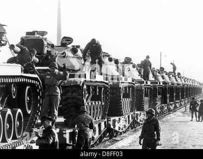 A railway servant (l) and several US soldiers check the securing of the US tanks, which have been loaded on a train for transport at the train station Lieblos in Hesse on the 5th of January in 1966. The tanks are part of the German-American manoeuvre 'Silberkralle', in which 22,000 soldiers of the 3rd US tank division and 3,000 German soldiers of the 15th tank brigade Koblenz were involved. Stock Photo