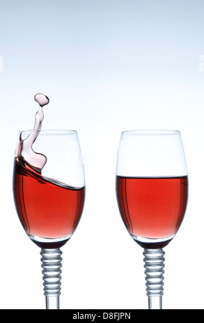 Two glasses of red wine with one splashing Stock Photo