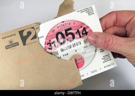 Opening an envelope containing a new UK road/car tax discs (UK car). Stock Photo