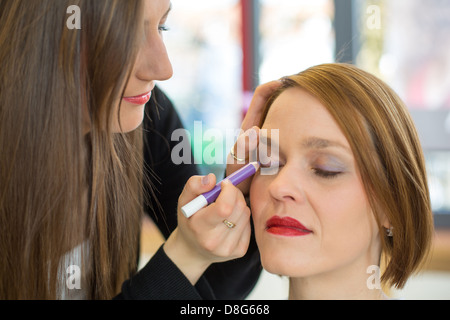 Cosmetician applying eye shadow to customer Stock Photo