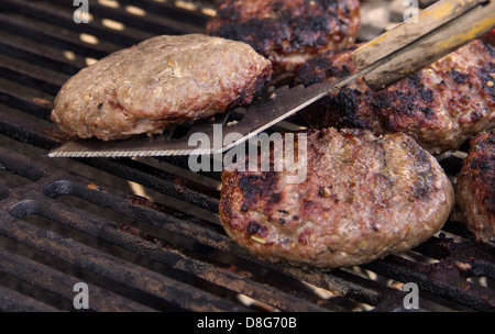 Hamburger patties being flipped on a grill Stock Photo