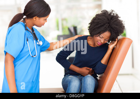 young African nurse comforting female patient in doctor's office Stock Photo