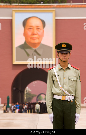 A young Chinese soldier stands at attention in front of Chairman Mao's portrait in Tiananmen Square. Stock Photo