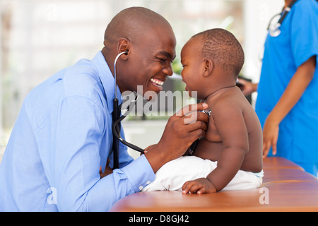 happy African male doctor examining baby boy with female nurse on background Stock Photo
