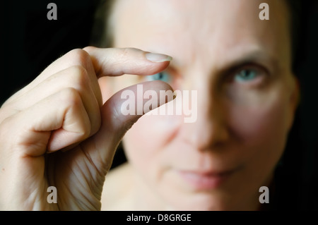 Fingers showing 'something little' - Blurred face in the background Stock Photo