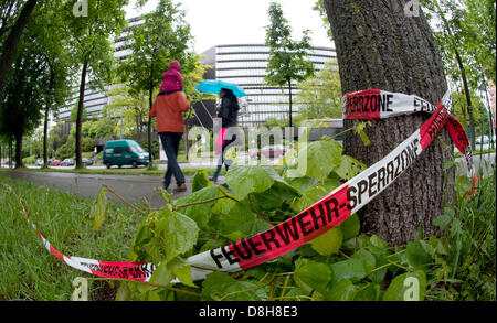 A red and white barrier tape of the fire brigade hangs on a tree in front of the European Patent Office (back) in Munich, Germany, 29 May 2013. On late 28 May, a 31 year old cyclist was severly injured by an unknown man and later died in hospital. Photo: PETER KNEFFEL Stock Photo