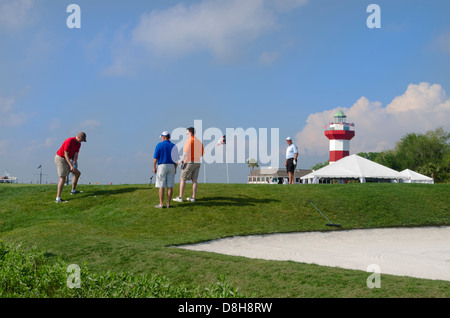 Golfers on 18th Hole at exclusive Habour Town Golf Links in Hilton Head South Carolina with famous red and white lighthouse Stock Photo