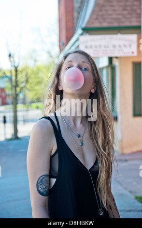 Young woman with tattoos blowing bubble gum Stock Photo