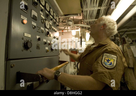 An engineer is seen working on a ship, focused on maintenance or repair tasks. The image highlights the technical work involved in ship operation and engineering. Stock Photo