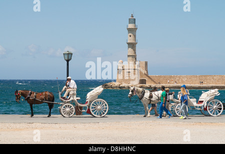 horses and carriages await tourists, Chania Venetian harbour, Crete Stock Photo