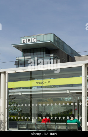 Seated passengers, one man, one woman, waiting at MediaCityUK tram station on the Manchester Metrolink, Salford Quays. Stock Photo