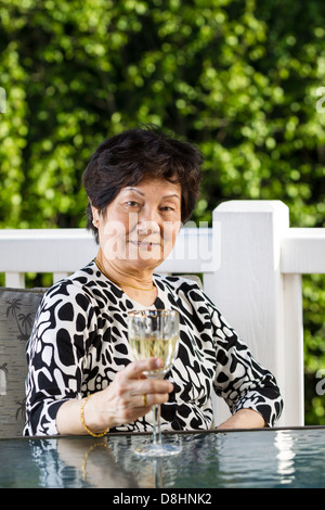 senior woman drinking white wine outdoors on the patio Stock Photo