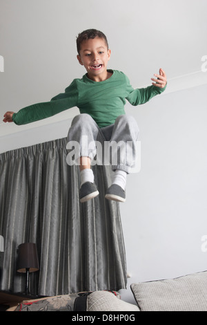 hyperactive child leaping off sofa Stock Photo