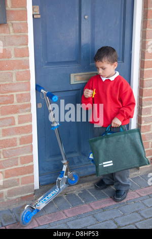 little boy arriving home from school with his scooter Stock Photo