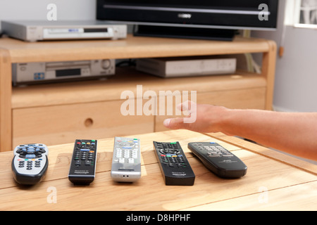 hand reaching for row of remote controls Stock Photo