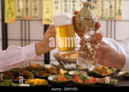Three People Toasting with Each Other With Various Drinks at Izakaya Stock Photo
