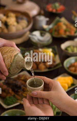 Two People Pouring and Receiving Sake at Izakaya Stock Photo