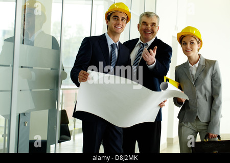 Three architects standing in office building and ooking at camera while planning work Stock Photo