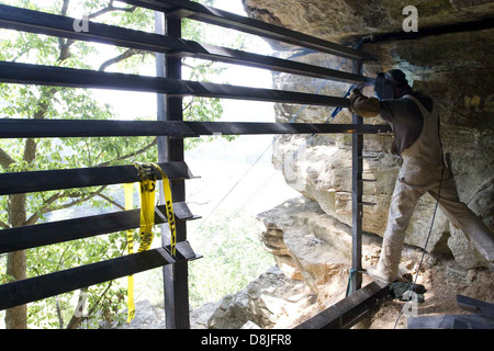 A worker installs a metal gate, using tools to secure it in place. Metal gates are commonly used for security, privacy, and boundary purposes in residential and commercial settings. Stock Photo