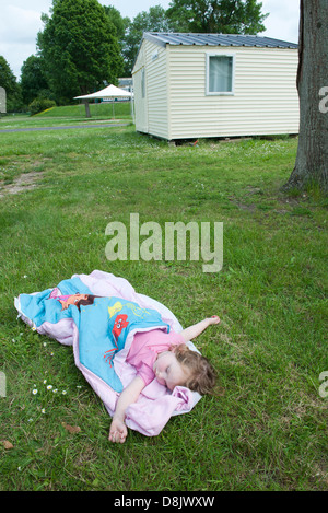 Little girl napping in sleeping bag on grass Stock Photo