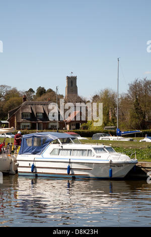 A boat moored on Malthouse Broad with Ranworth Church in the background, Norfolk Broads, England UK Stock Photo