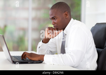 thoughtful young African American businessman working on laptop computer Stock Photo