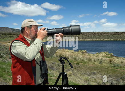 A volunteer photographer captures images during an event. The photographer is actively engaged in taking shots, contributing their skills to help document and support the event or cause. The scene portrays an individual using professional equipment, focusing on the subject matter with precision and care, offering their time and talents for a good cause. Stock Photo