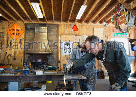 Senior metalworker advising female apprentice at workbench
