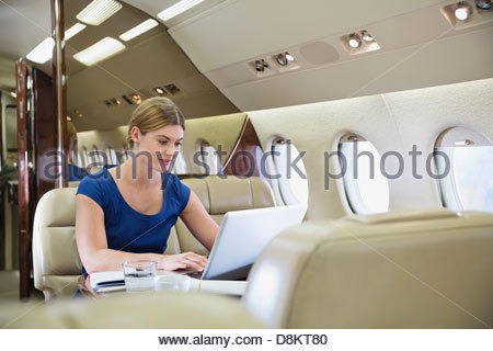 Young businesswoman using laptop in airplane