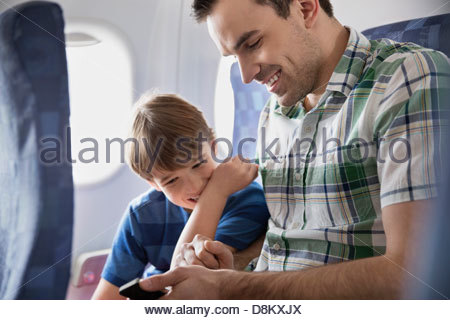 Father and son using smartphone in airplane