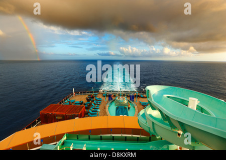 Cruise line ship sailing in a storm with a rainbow on the horizon Stock Photo