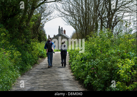 A young family walking down a road into Penberth Cove in Cornwall. Stock Photo