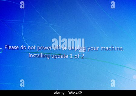 Windows Update message on screen 'Please do not power off or unplug your machine.  Installing update 1 of 2' Stock Photo