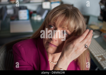 Woman in office wiping her eye. Stock Photo