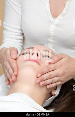 Cosmetician giving client a facial massage Stock Photo