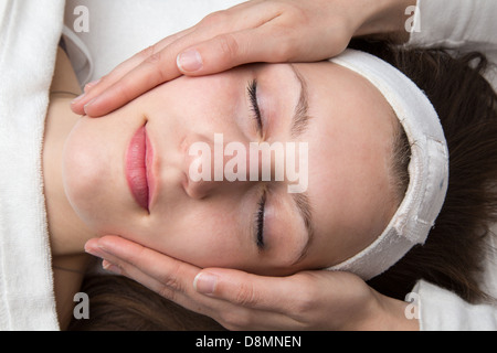 Cosmetician giving client a facial massage Stock Photo