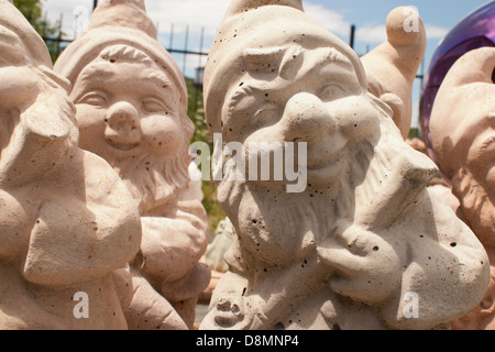 Cement gnomes for sale peer into the camera at a roadside business. Stock Photo