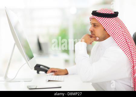 middle eastern businessman looking on a computer screen, sitting in his office Stock Photo
