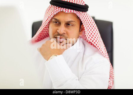 thoughtful arabic businessman looking at computer screen Stock Photo